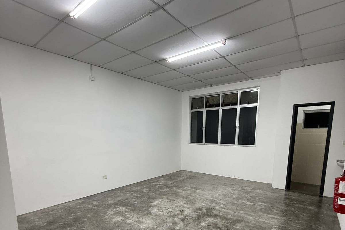 A partitioned office room with a suspended mineral-fibre ceiling grid, surface-mounted LED battens, a band of windows and a bare power-floated concrete floor.